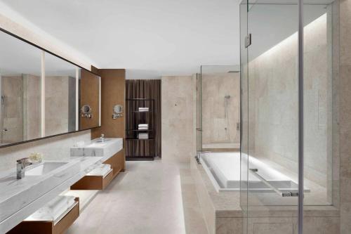 ein Badezimmer mit zwei Waschbecken, einer Badewanne und einer Dusche in der Unterkunft Jiaxing Marriott Hotel in Jiaxing