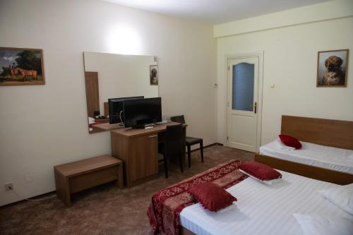 a hotel room with two beds and a desk and a mirror at Hotel Panoramic in Râmnicu Vâlcea