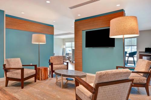 a living room with chairs and a table and a tv at TownePlace Suites by Marriott Panama City Beach Pier Park in Panama City Beach