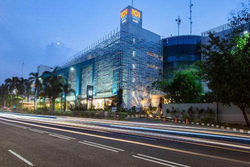 a large glass building with a clock tower on a street at 1O1 URBAN Jakarta Kelapa Gading in Jakarta