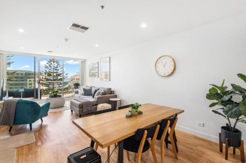 a living room with a table and chairs and a clock at Belle Escapes - Aquarius on Colley Terrace 2 bed-2bath with sea views in Glenelg