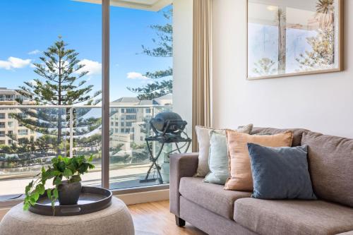a living room with a couch and a large window at Belle Escapes - Aquarius on Colley Terrace 2 bed-2bath with sea views in Glenelg