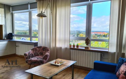 a living room with a table and chairs and windows at Art Apartamenty Złota in Kalisz