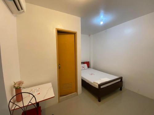 um pequeno quarto com uma cama e uma porta amarela em WJV INN MARIBAG0 em Maribago