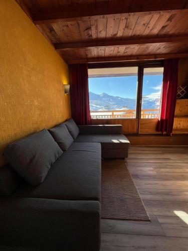 ein Wohnzimmer mit einem Sofa und einem großen Fenster in der Unterkunft Cosy Apartment Val Thorens in Val Thorens