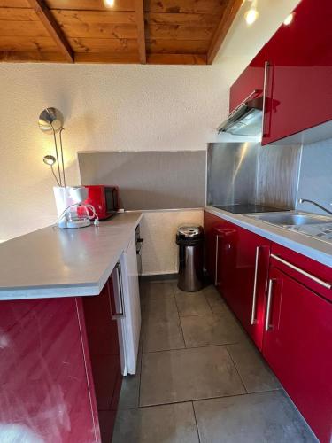 eine kleine Küche mit roten Schränken und einem Waschbecken in der Unterkunft Cosy Apartment Val Thorens in Val Thorens