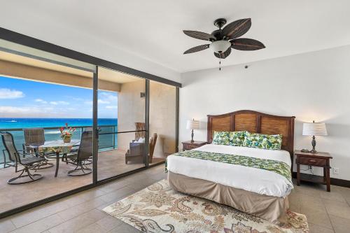 a bedroom with a bed and a balcony with the ocean at Sands of Kahana 354 in Kahana