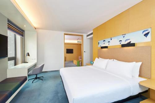 Habitación de hotel con cama blanca grande y escritorio. en Aloft Zhengzhou Shangjie en Zhengzhou