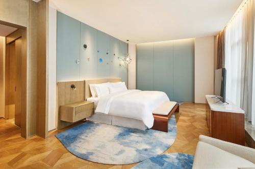 1 dormitorio con 1 cama y TV en The Westin Qingdao West Coast, en Huangdao