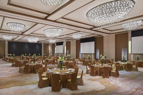 a banquet hall with tables and chairs and chandeliers at Sheraton Yunfu Xinxing Hotel in Yunfu