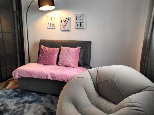 AmoroyにあるPerlizas HomeStay NO FREE BREAKFAST INCLUDEDのピンクの枕と椅子が備わる客室のベッド1台分です。
