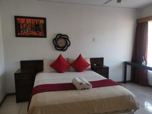 ein Schlafzimmer mit einem großen Bett mit roten Kissen in der Unterkunft Rose Guest House in Pretoria