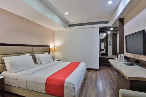 a hotel room with a bed and a television at Krios Hotel - Near SG Highway, Ahmedabad in Ahmedabad