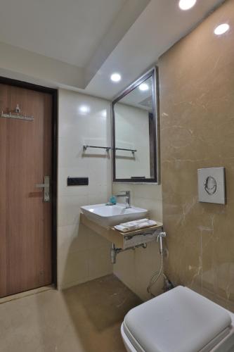 a bathroom with a sink and a toilet and a mirror at Krios Hotel in Ahmedabad