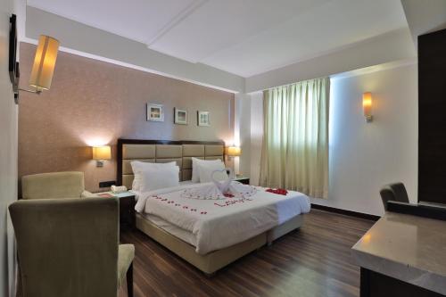 a hotel room with a bed and a chair at Krios Hotel - Near SG Highway, Ahmedabad in Ahmedabad
