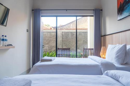 two beds in a bedroom with a large window at Rabasta Enjoy Kuta in Denpasar