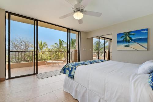 a bedroom with a bed and a balcony with sliding glass doors at Paki Maui 424 in Kahana