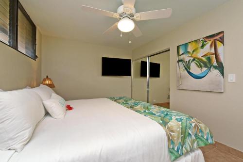 a bedroom with a white bed and a ceiling fan at Paki Maui 424 · PM424 BeachFront 2BD w Ocean View in Kahana