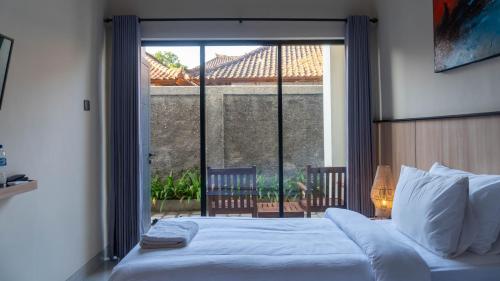 a bedroom with a bed and a large window at Rabasta Enjoy Kuta in Denpasar