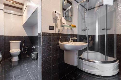 a bathroom with a sink and a shower and a toilet at Old City Tower Inn in Baku