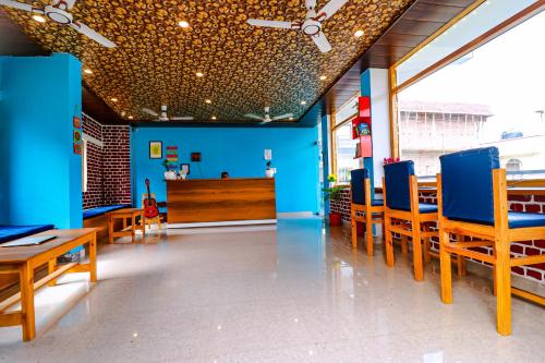 um restaurante com paredes azuis e mesas e cadeiras de madeira em Manzil Hostel em Rishikesh