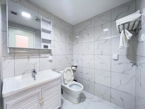 a white bathroom with a toilet and a sink at Guangzhou Zhicheng Leader Tour International Apartment in Guangzhou