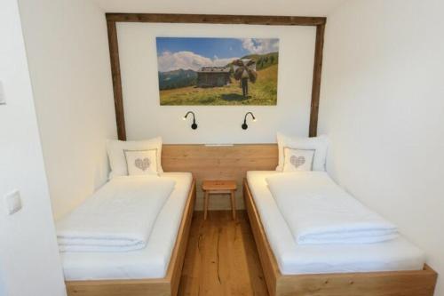 サンタ・マッダレーナ・イン・カジーエスにあるAusserharmerhof App Wiesenglückの壁に絵が飾られた部屋にベッドが2つある