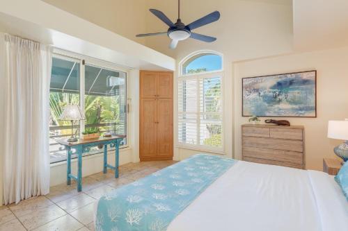 a bedroom with a bed and a desk and windows at Palms at Wailea 2108 in Wailea
