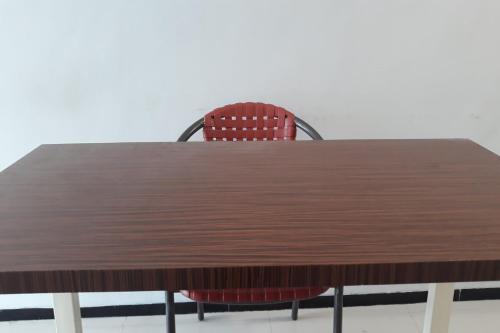 un tavolo in legno con una sedia rossa intorno di OYO Life 2678 Manyar Guest House a Surabaya