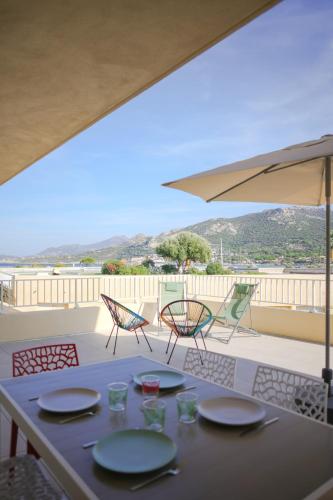 - une table avec 4 chaises et un parasol sur la terrasse dans l'établissement Appartement La Balagne , Bord de mer, Grande Terrasse, Sant'Ambroggio, à Lumio