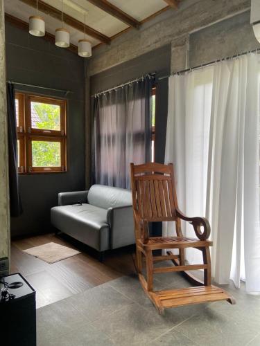 uma sala de estar com uma cadeira e um sofá em Forest Guesthouse em Ban Don Muang