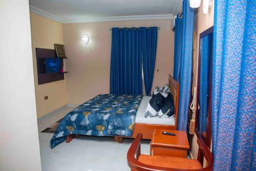 a bedroom with a bed and blue curtains at Cogent Apartments in Uyo