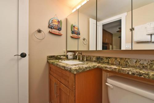 een badkamer met een wastafel, een spiegel en een toilet bij Pacific Shores B102 in Kihei