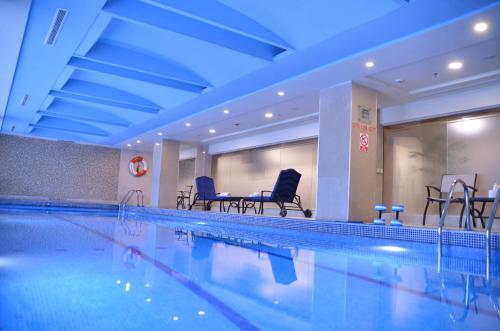 a large swimming pool with chairs and a table at Islamabad Marriott Hotel in Islamabad