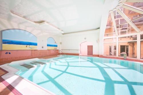 a large swimming pool in a building with a large window at Strandhotel Preussenhof in Zinnowitz