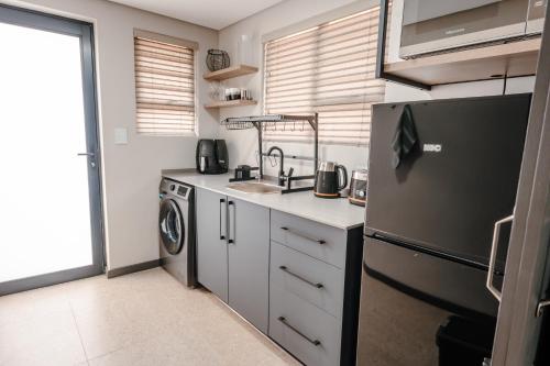 a kitchen with a refrigerator and a sink and a dishwasher at 80 on Thabo in Potchefstroom