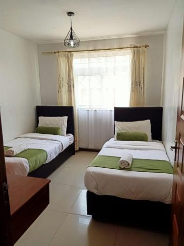 two beds in a room with a window at Furnished Homes Nakuru with pool & GYM in Nakuru