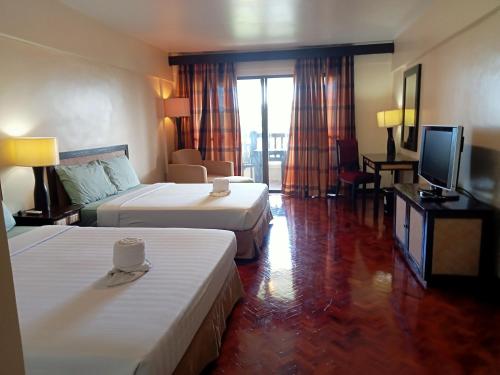 a hotel room with two beds and a flat screen tv at Keira 208, Alta Vista De Boracay in Boracay