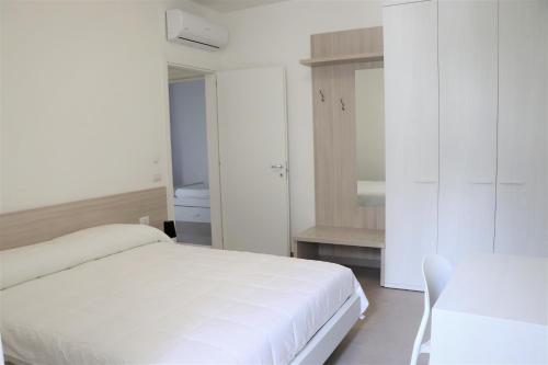 una camera bianca con letto e armadietto bianco di Verde Blu Vacanze Suites a Porto Cesareo