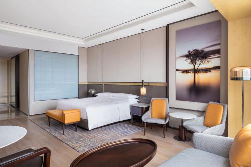 a hotel room with a bed and tables and chairs at Sheraton Shanghai Fengxian in Shanghai
