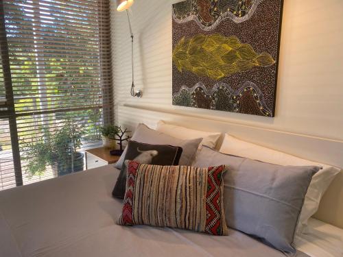 a bedroom with a bed with pillows and a painting at Moriarty Retreat - couple's luxe getaway in Yallingup