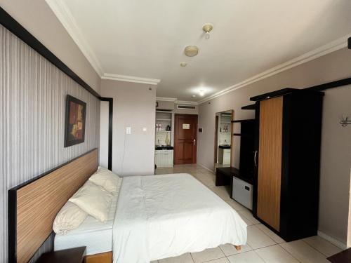 ein Schlafzimmer mit einem großen weißen Bett und einem TV in der Unterkunft Studio at Grand Setiabudi Apartment in Bandung