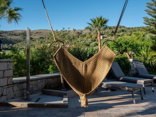 a hammock hanging from a patio with chairs and palm trees at Kipo Paradiso Spa, Yoga & Gym Resort in Kiriánna