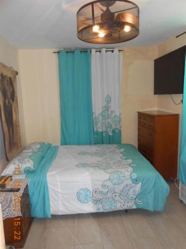 una camera da letto con letto con tende blu e televisore di Gustave Vacation House a Port-au-Prince