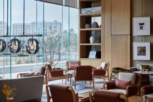 a waiting room with chairs and tables and a large window at Wenzhou Airport Marriott Hotel in Wenzhou