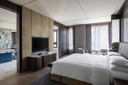 um quarto de hotel com uma cama grande e uma televisão em Wuhan Marriott Hotel Optics Valley em Wuhan