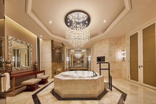 un bagno con una grande vasca e un lampadario a braccio di 福州天元国际威斯汀酒店 a Fuzhou