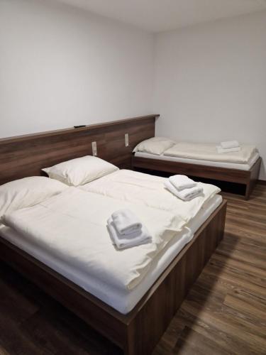two beds with white sheets and towels on top of them at Hotel Grand in Doksy