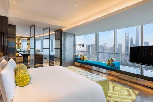 a bedroom with a large white bed and a tv at W Shanghai - The Bund in Shanghai
