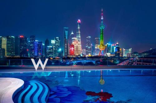 a pool with a view of the city at night at W Shanghai - The Bund in Shanghai